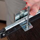 tightening a screw on a pull out shelf in a cabinet