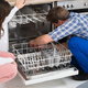 A man looks at a dishwasher.
