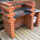 An outdoor, brick grill on a deck.