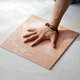 Hand on a square of porcelain tile.