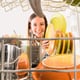 smiling woman loading or unloading dishwasher
