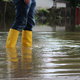 A woman wears yellow rain boots in a flood.