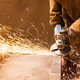 sparks fly as a person with gloves uses an angle grinder