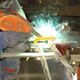 A worker in a fabrication shop welding aluminum.