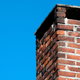 A worn, brick chimney against a blue sky.