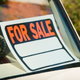 A "for sale" sign sits in the windshield of a car.