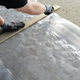 hands cutting plastic sheeting along a wooden frame