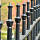 A close-up of a black iron fence with pointed slats. 