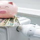 A piggy bank sitting on top of a stack of cash on a heater.