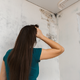 woman looking at mold in the corner of a room