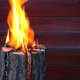 A tree stump against a wall or fence, flames emitting from the top of the stump