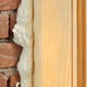 A polyurethane layer squeezing out between a wood frame and a brick wall.