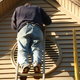 man on ladder facing vinyl siding of house