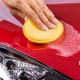 hand applying wax to red car with pad