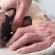 A staple gun being used to secure fabric to a wooden backing.