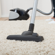 a woman vacuuming a cream colored area rug