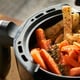 herbed carrots and potatoes cooking in an air fryer