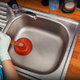A plunger being used to unclog a kitchen sink.