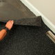 A worker installs a section of recycled rubber floor onto an adhesive covered concrete slab.