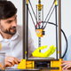 man and woman smiling at 3D printer making hand model