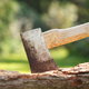 An axe with a wooden handle embedded in a log.
