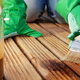 person with gloves and brush staining deck wood