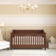 A wooden crib in a neutral baby room.