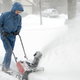 A man using a snowblower in his yard.