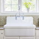 A white kitchen sink in front of a window with a beige interior.