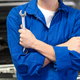 mechanic holding wrench in front of a car