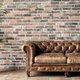 leather couch with houseplant and brick wall