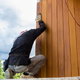 man installing pine lumber home siding