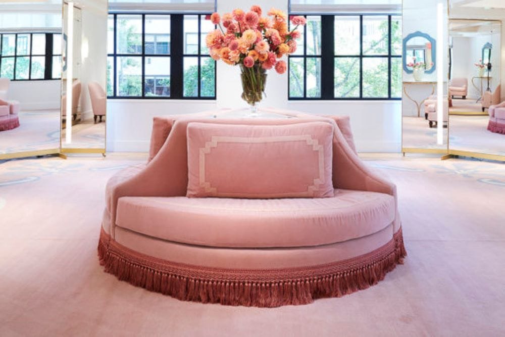 An elegant pink couch adorned with a fringe border. 