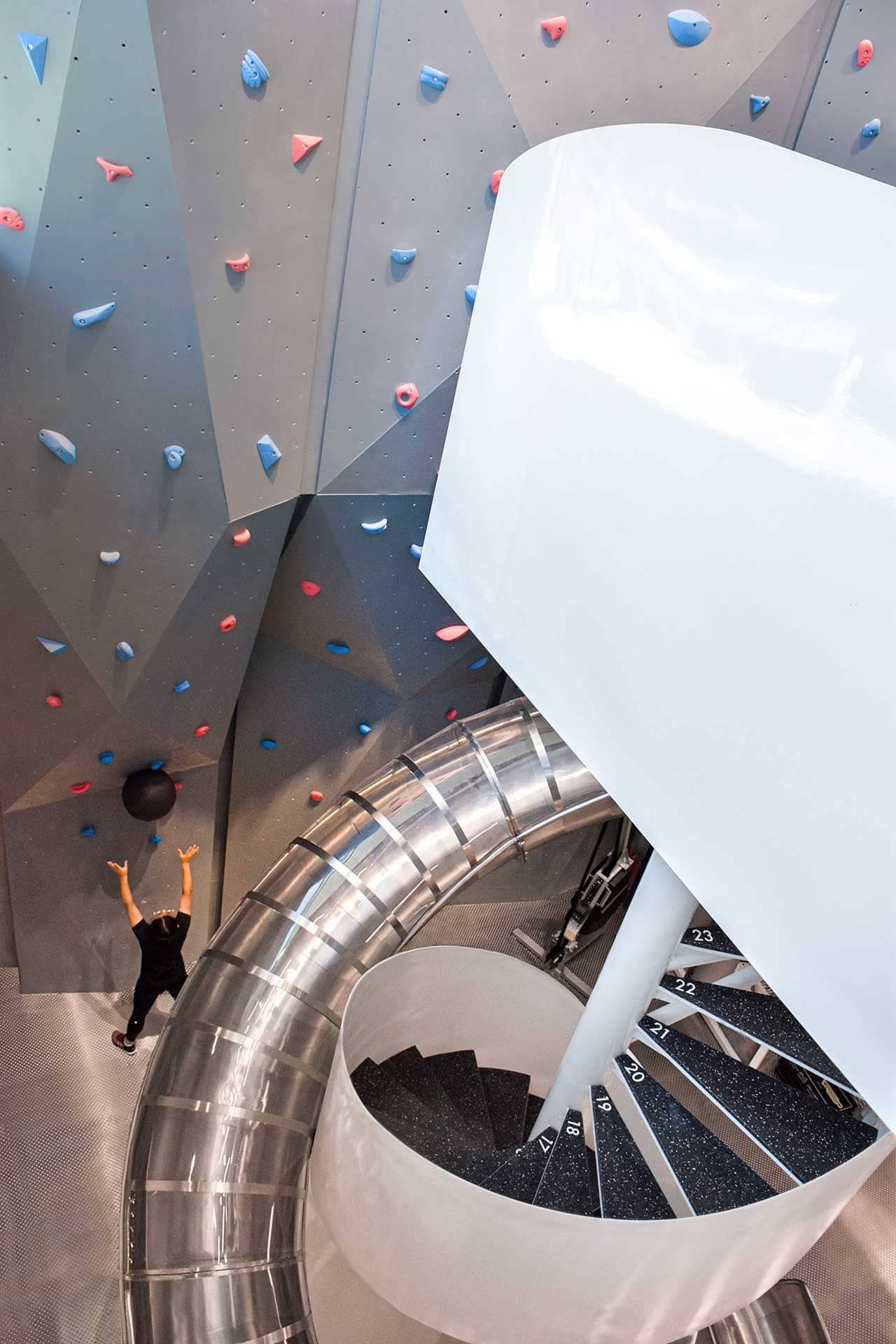 A large climbing wall sits right next to MFIT SPACE 01's spiraling metallic slide.
