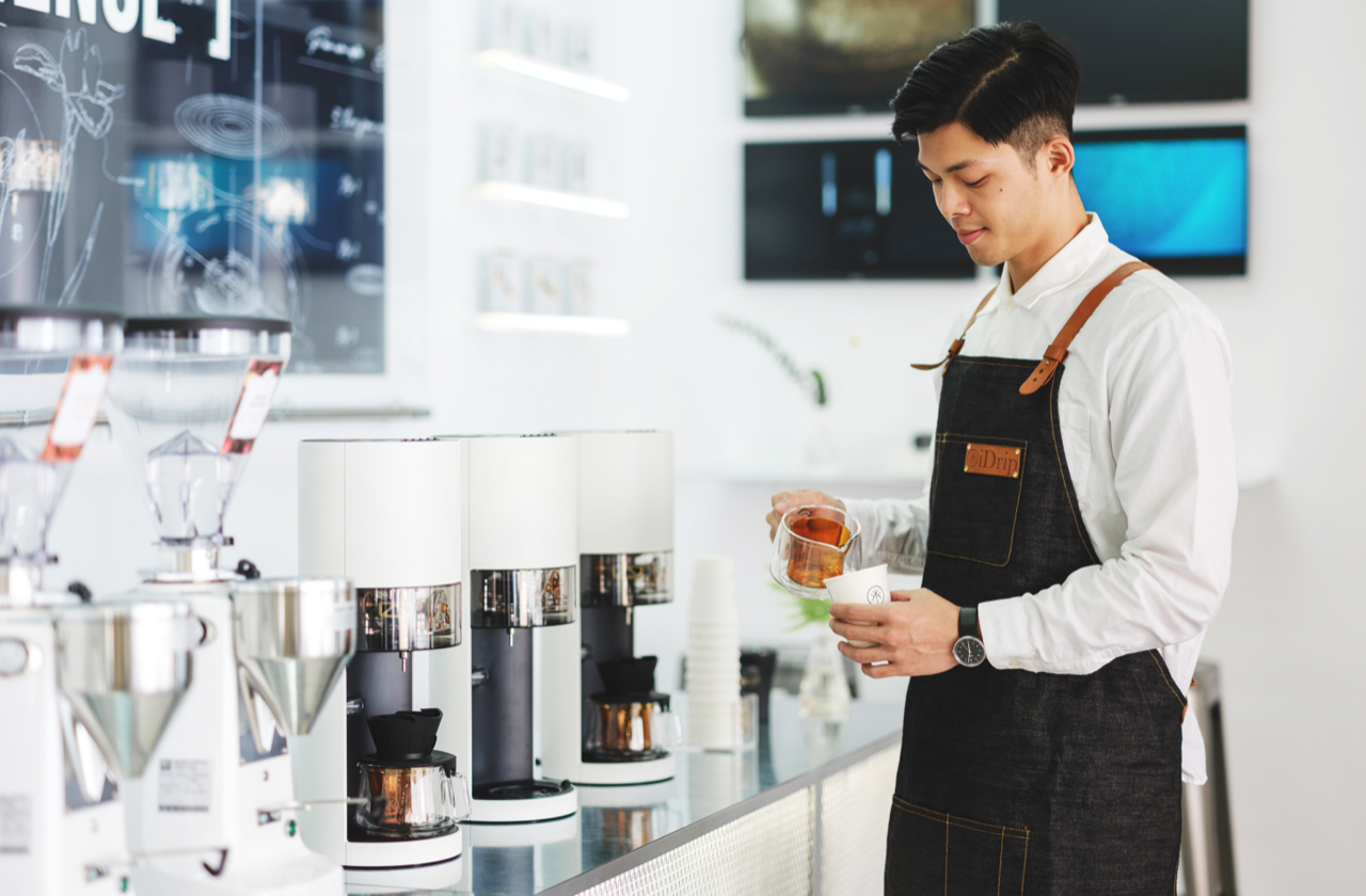 Expert Barista scientifically prepares gourmet coffee at iDrip's Smart Pour-Over Coffeemaker exhibition space.