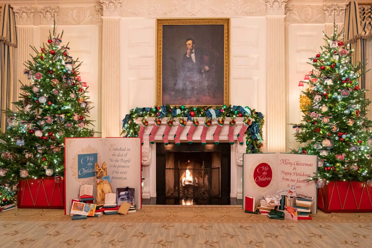 White House State Dining Room adorned with stockings, oversized cards, and Christmas trees for the 2022 holiday season.