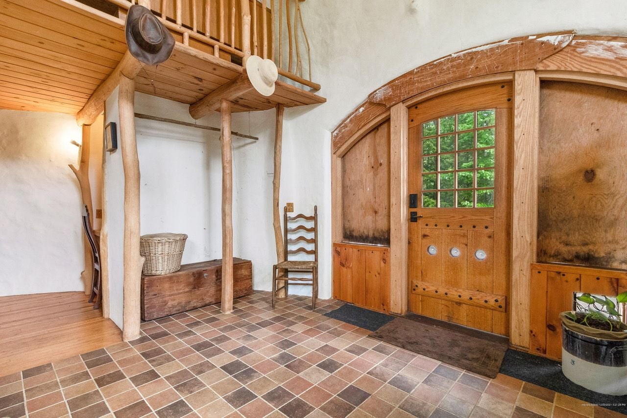 Charming rustic entryway inside the 34 Road to Misery Dome Home, complete with log-like wooden beams and tile flooring. 