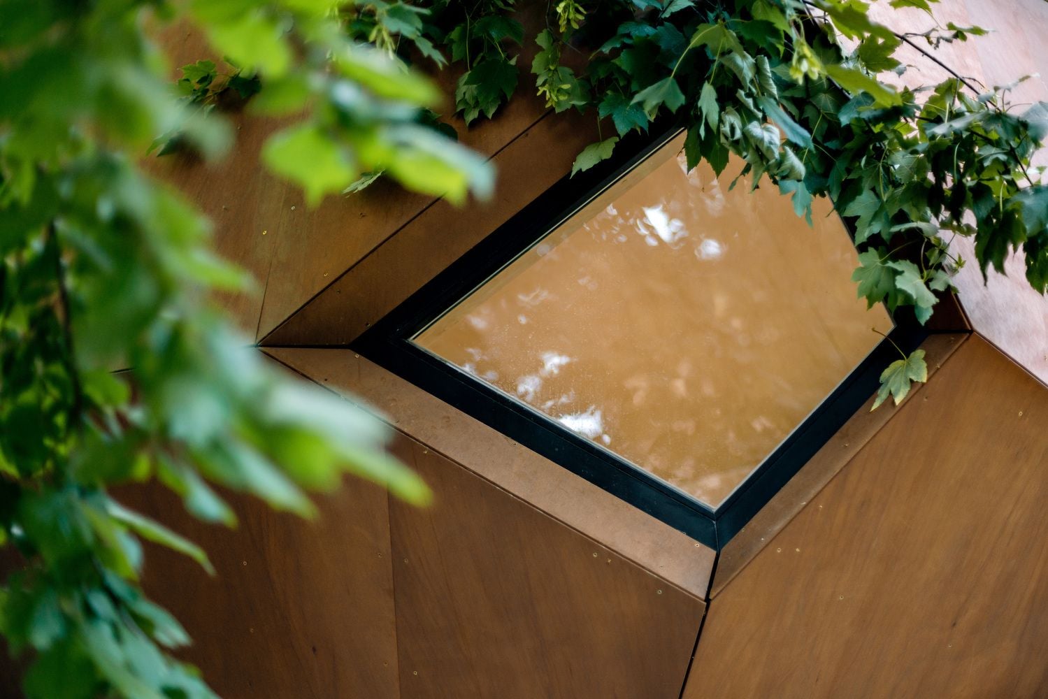 Close-up shot of a small geometric window set into the Workstation Cabin's otherwise all-wooden exterior.