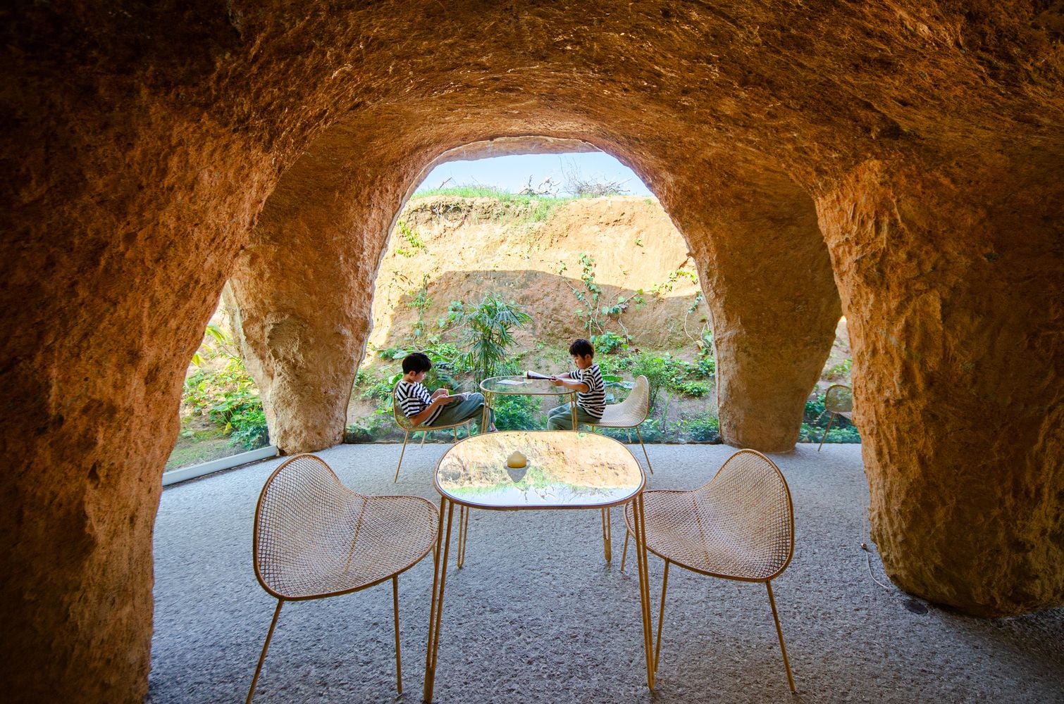 Two children sit at one of the House and Restaurant Cave's small patio tables.