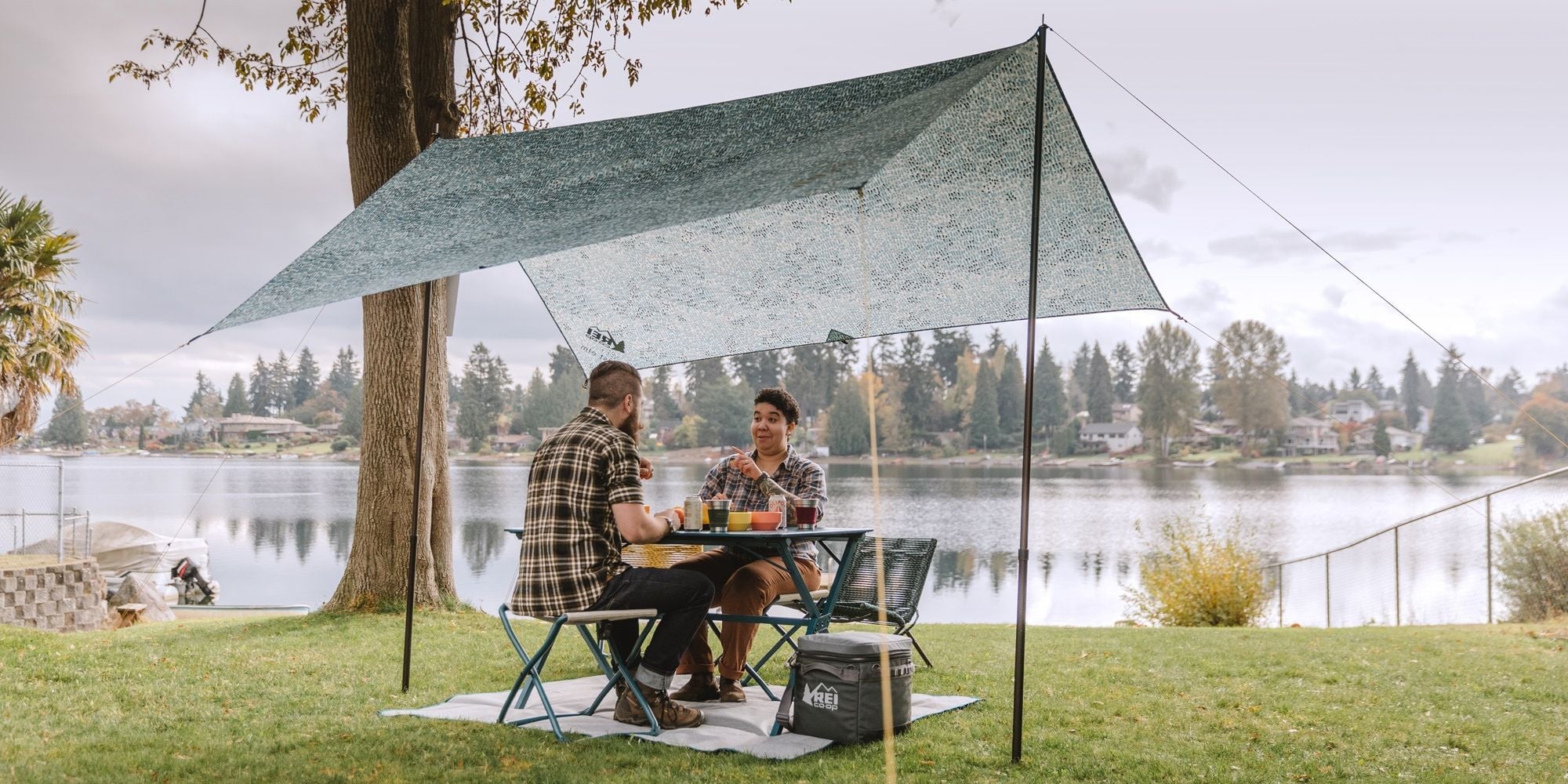 Two friends enjoy an outdoor picnic under the cover of West Elm and REI's new Outward Day Shelter. 