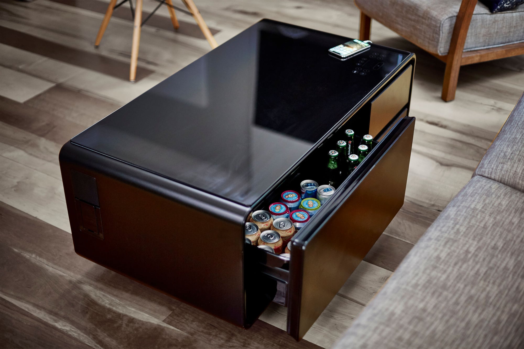 The Sobro Smart Coffee Table set up in a contemporary living room, with its refrigerated drinks drawer pulled slightly open. 