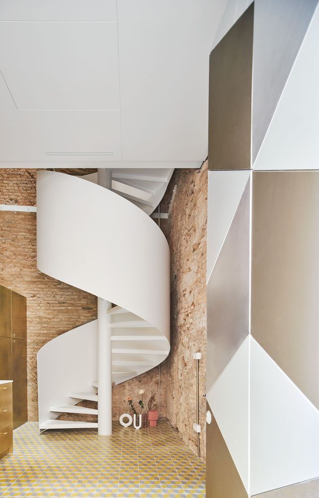 Pristine white spiral staircase in the renovated BSP 20 apartment beautifully contrasts the home's exposed brick walls.