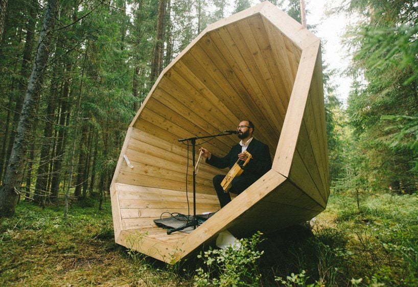 A musician pays and sings inside one of the giant wooden megaphones. 