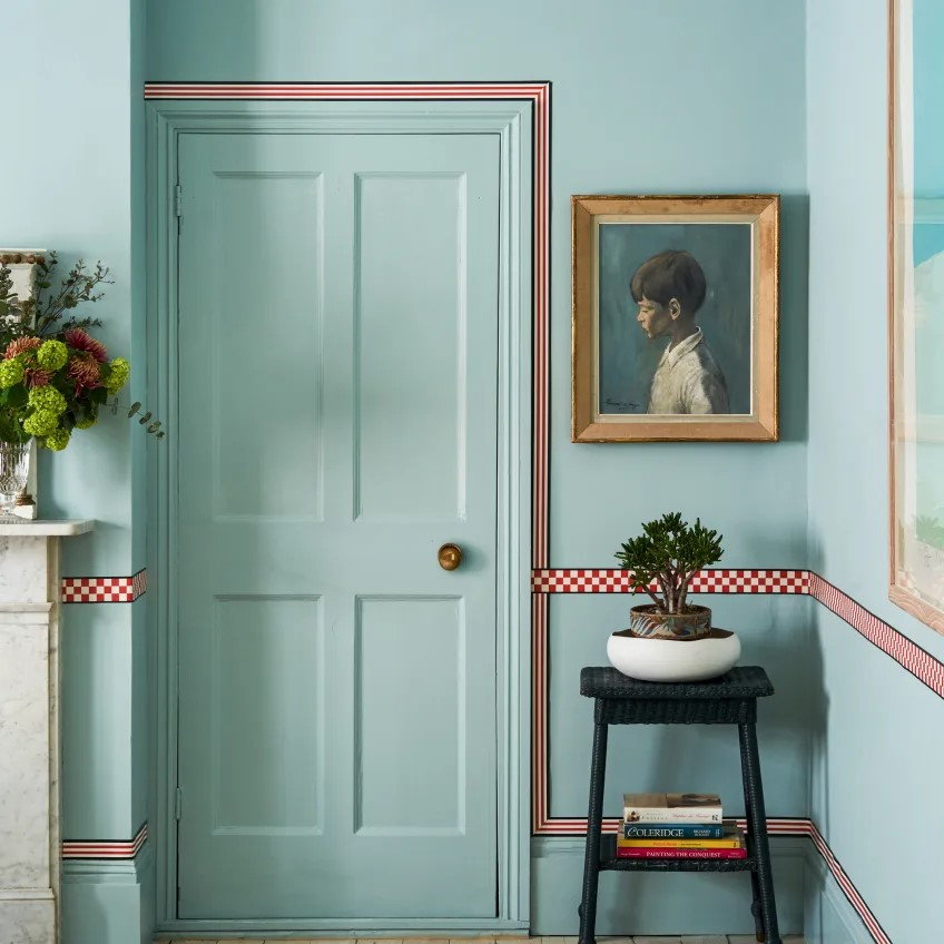 Colorful wallpaper border ramps up the chair rail and doorframe in this pastel living space.
