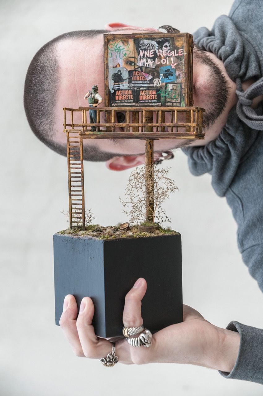 Artist Simon Laveueve holds up one of his haunting dystopian miniatures.