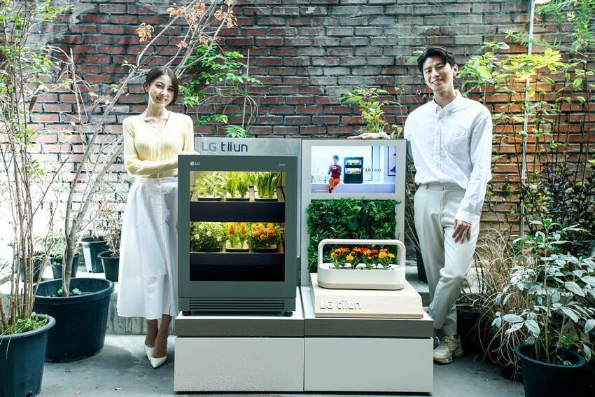Man and woman proudly display the LG Tiuun smart gardening appliance at CES 2022.