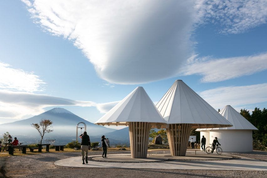 Ground view of Kengo Kuma's Mt. Fuji-inspired public toilets in Japan, with the actual mountain visible in the background.