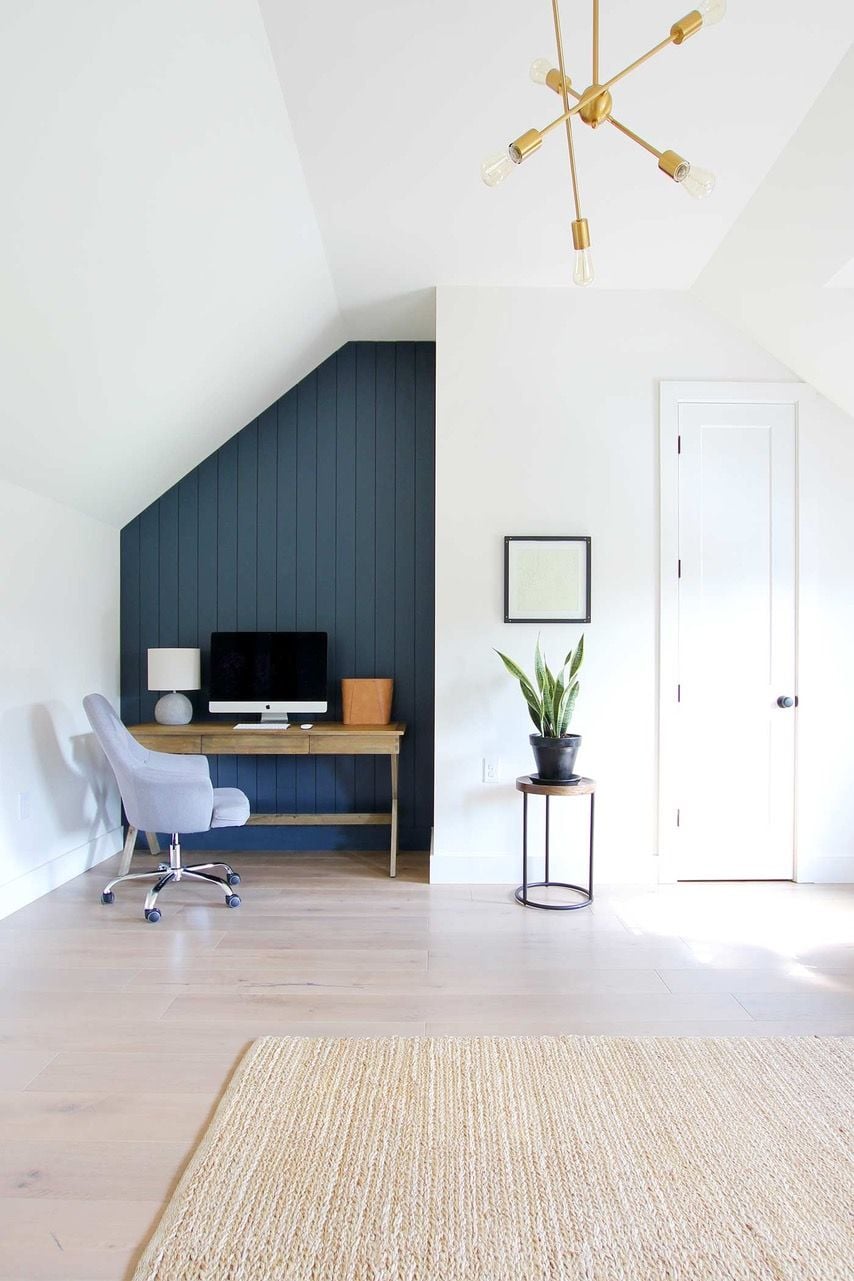 The shiplap accent wall in this modern home office is painted a deep, calming blue 
