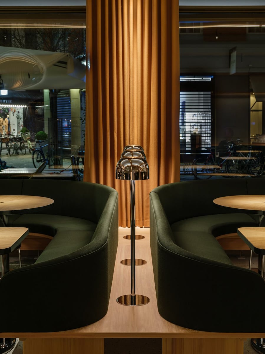 Sleek modern lighting fixtures line the spaces between booths inside Copenhagen's Restaurant Levi.