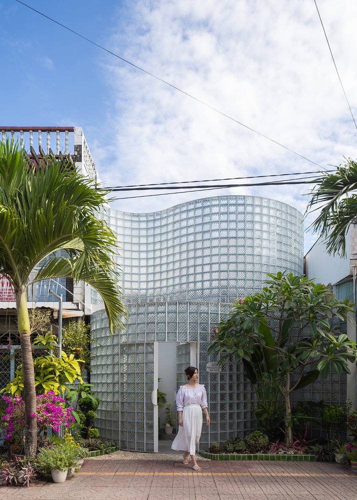 Woman steps outside the curving glass facade of the Coco House.